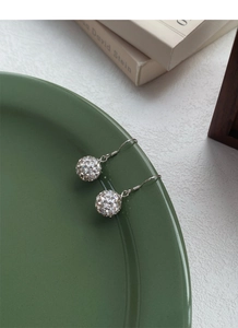 Detail of silver S925 drop earrings with crystal disco balls on dark green plate