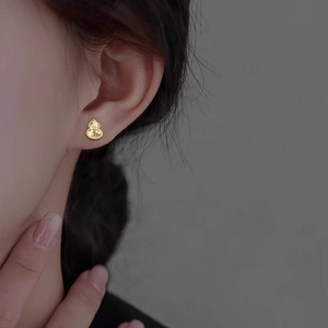 Elegant gold gourd-shaped stud earrings with sparkling honeycomb texture on model