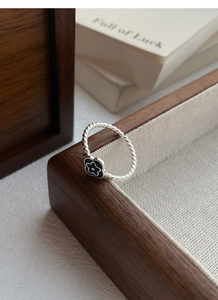 Detailed macro view of S925 silver twist ring featuring a black enamel flower charm
