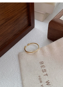 Detail of a minimalist gold twisted rope open ring on a warm vintage background