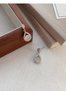 Macro shot of silver teardrop earrings with white chalcedony and zirconia accents