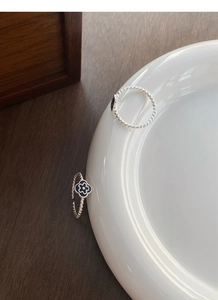 Detail view of S925 sterling silver ring with twisted rope texture and black flower motif