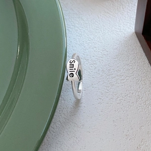 Minimalist S925 sterling silver fish ring with Smile engraving on a ceramic dish