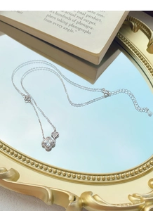 Gros plan du collier trèfle en argent S925 avec incrustation de zircon sur un miroir