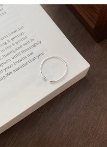 Macro shot of minimalist S925 sterling silver twisted rope open ring on a book page
