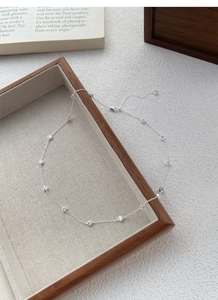 Detail of S925 sterling silver necklace with zircon stations on a wooden tray