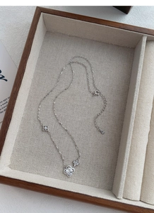 Détail macro du collier trèfle en argent S925 avec cristal carré dans un coffret bois