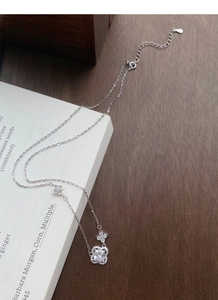 Gros plan du collier trèfle en argent S925 avec zircon carré sur un livre blanc