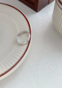 Détail d'une bague en argent S999 avec petits zircons sur une assiette en céramique
