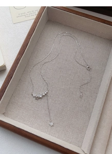 Detail of silver star tassel necklace with sparkling zircon on a linen display tray