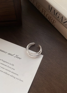 Dettaglio dell'anello multistrato in argento S925 ritorto su carta bianca