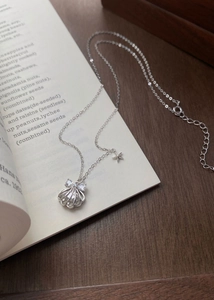 Détail du pendentif coquillage en argent S999 avec étoile sur fond de livre ouvert