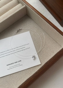 Macro view of heart-shaped zircon pendant with transparent fishing line on wooden box