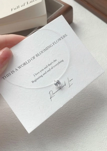 Detail of a heart-shaped zircon pendant on invisible fish line with gift message card