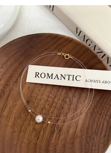 Detail shot of a minimalist 8mm pearl pendant on a transparent fishing line necklace