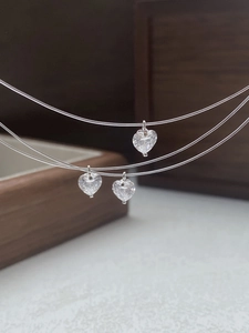 Macro shot of three S925 silver heart zircon pendants on transparent fishing line chains
