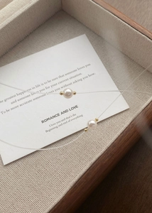 Minimalist pearl necklace with invisible fish line and gold beads on a wooden tray
