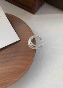 Dettaglio anello in argento S925 con fasce intrecciate lisce e texture a corda ritorta