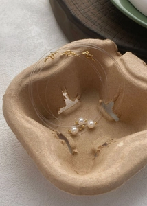 Detailed macro of minimalist floating pearl necklaces on rustic pulp tray