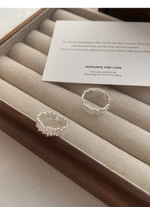 Detailed view of two irregular lava texture S925 silver open rings in a wooden jewelry box