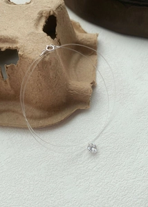 Close-up of heart-shaped zircon pendant on invisible nylon wire necklace with silver clasp