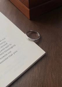 Détail d'une bague en argent brossé avec un petit diamant sur un livre ouvert
