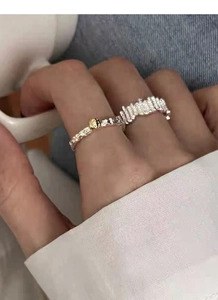 Detail of silver S925 rings with irregular texture and gold bead on a model's hand