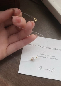 Detail of a floating pearl pendant on invisible fishline with gold spring clasp