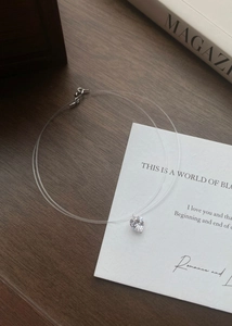 Detail view of heart-shaped zircon pendant on a transparent fishing line necklace
