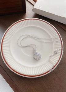 Detail of S925 silver necklace with white chalcedony pendant on a ceramic tray