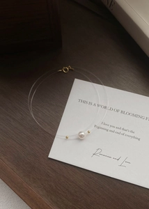 Detailed macro view of minimalist S925 silver necklace with single pearl on invisible fishing line