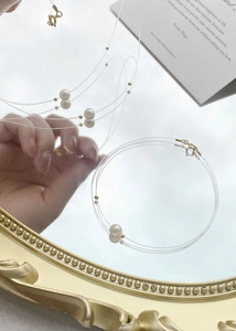 Detail of S925 silver pearl necklace on gold mirror with multi-layer invisible wire