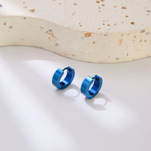Modern minimalist blue stainless steel hoop earrings for men on textured display