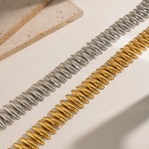 Polierte Silber- und Gold-Gliederkettenarmbänder auf strukturiertem Stein-Hintergrund