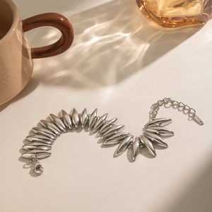 Detail eines silbernen Edelstahl-Olivenperlenarmbands mit Karabinerverschluss und Kette