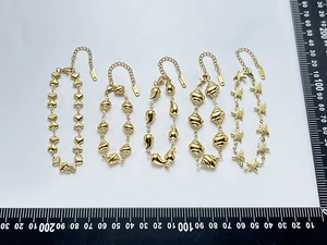 Detail showing five gold stainless steel bracelet designs with heart and shell charms