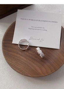 Close-up of S925 silver rings with beaded and textured surface on a wooden tray