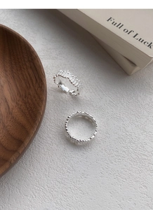 Detailed macro view of S925 silver rings with irregular lava texture on white background