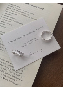 Close-up of S925 sterling silver rings with unique irregular textured surface on aesthetic card