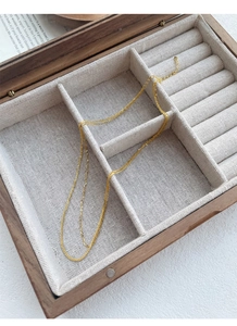 Detail van een gouden sterling zilveren Chopin-ketting in een rustiek houten sieradendoosje