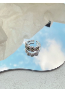 Macro di anello in argento con texture lavica e tre zirconi verdi con riflesso sullo specchio