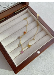 Gros plan d'un bracelet en argent S925 doré avec pendentifs trèfles sertis de gemmes