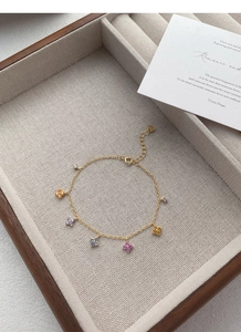 Détail macro d'un bracelet en argent S925 doré avec des trèfles à quatre feuilles colorés