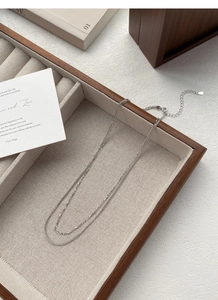 Detailopname van een S925 sterling zilveren dubbellaagse ketting op een beige plateau