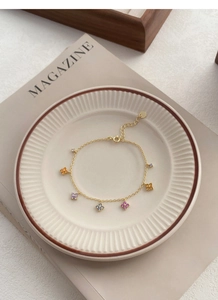 Vue macro du bracelet trèfle doré avec gemmes multicolores sur une élégante assiette