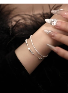 Detail of a double-layered S925 silver bracelet featuring star charms and beaded textures