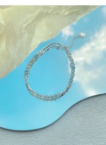 Dettaglio della chiusura in argento S925 e perle di acquamarina blu riflesse nello specchio