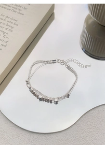 Detail of S925 sterling silver layered bracelet featuring star pendants and S925 hallmark