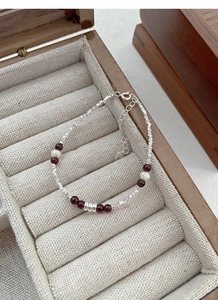 Detailed shot of S925 silver bracelet with red garnets and pearls on a velvet display