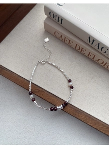 Macro detail of S925 silver bracelet featuring natural garnet beads and white pearls